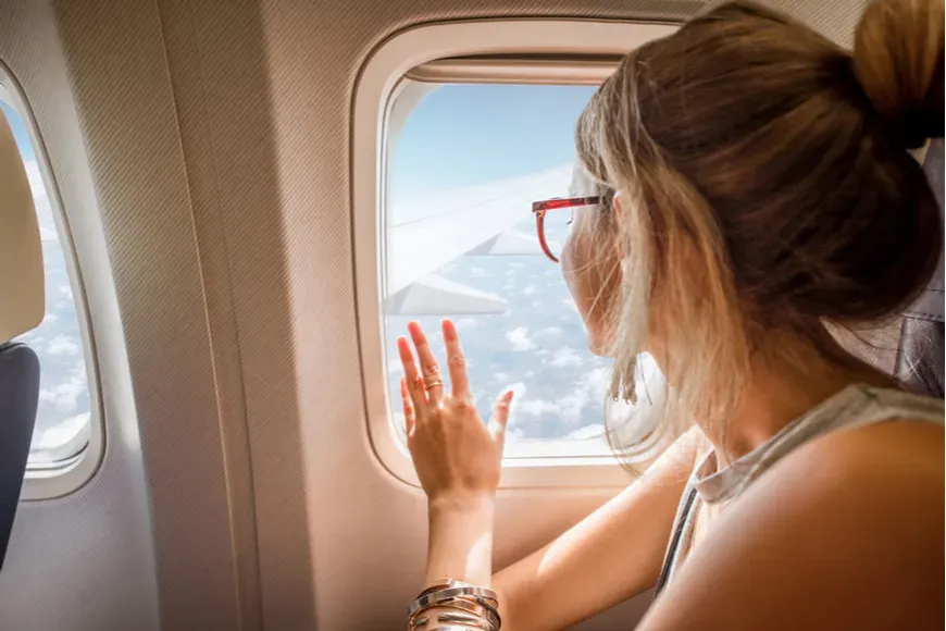 girl with glasses staring out plane window.
